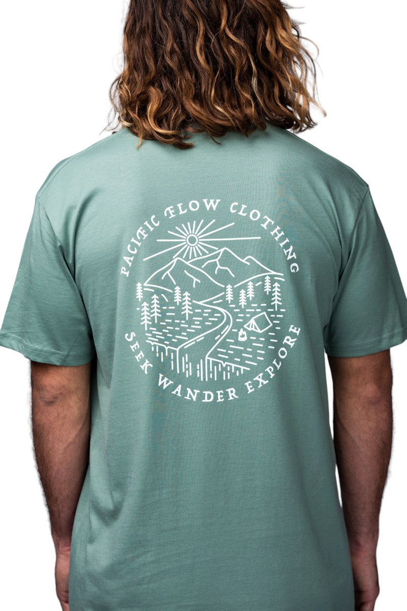 A green shirt with the mountains a river, the sun, and evergreen trees.