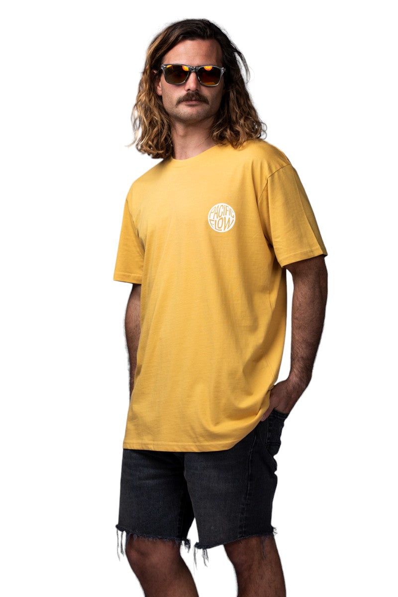A mustard coloured shirt with an island on the back, with surfboards, a fire, palmtrees, a tent, and waves to surf.