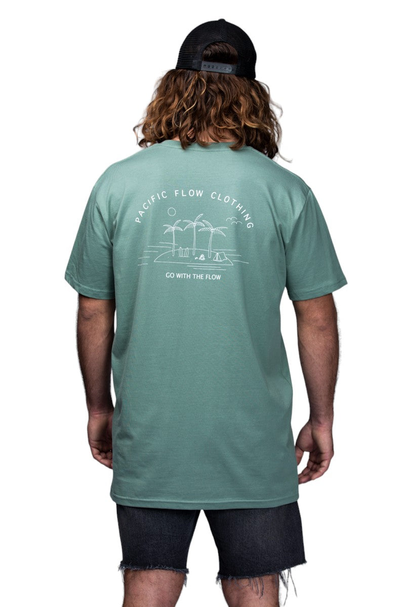 A sage coloured shirt with an island on the back, with surfboards, a fire, palmtrees, a tent, and waves to surf.