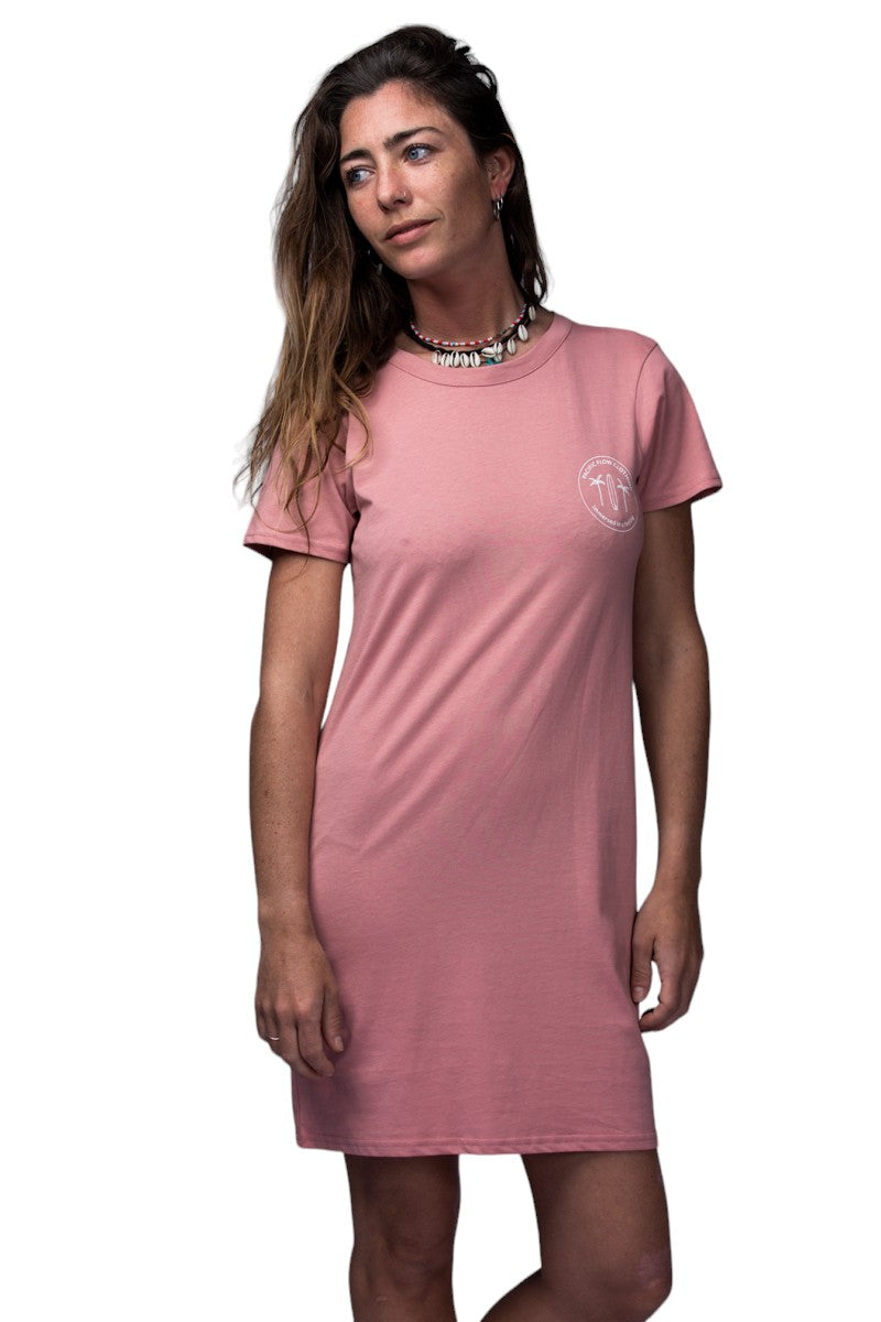A rose coloured dress with an island on the back, with surfboards, a fire, palmtrees, a tent, and waves to surf.